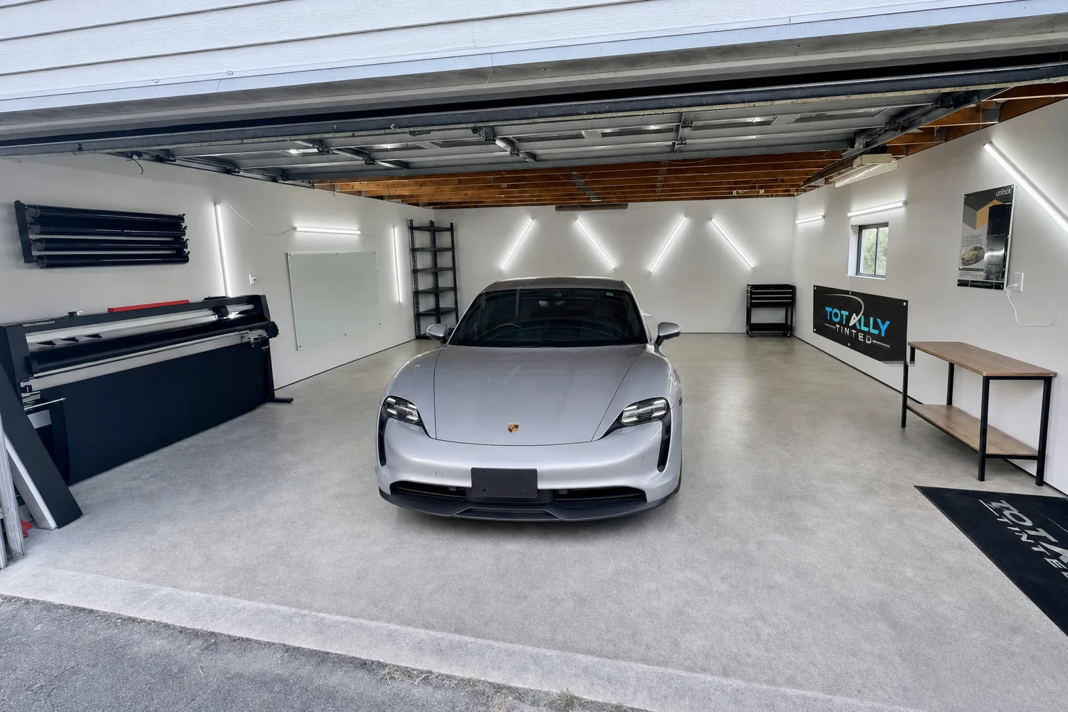 Liquid silver Porsche Taycan with freshly tinted windows in the Totally Tinted garage studio