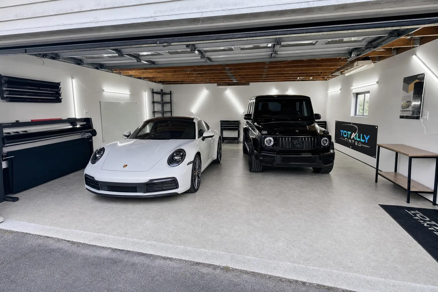 Pearl white Porsche 911 Carrera and gloss black Mercedes-Benz G-Class with freshly tinted windows in the Totally Tinted garage studio