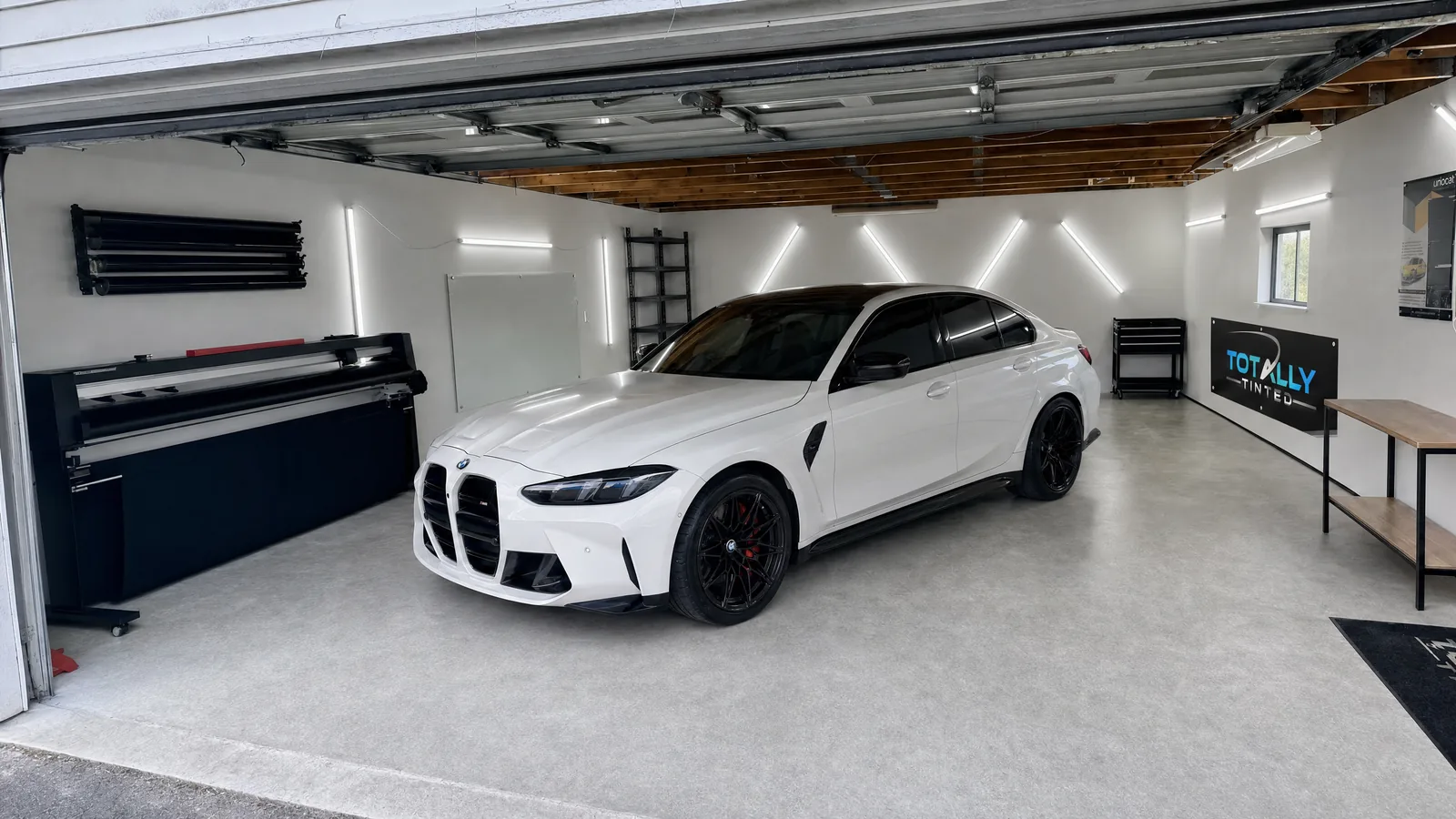 Alpine White BMW M3 Competition sedan with freshly tinted windows in the Totally Tinted garage studio
